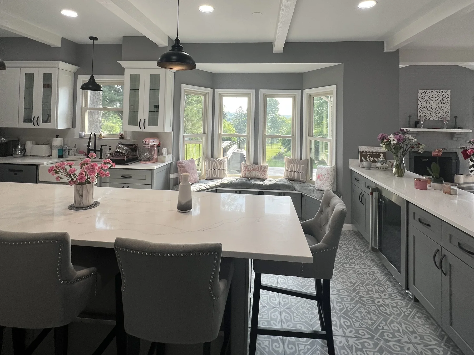 Modern kitchen with white and gray cabinets, island, window seat, and pendant lighting